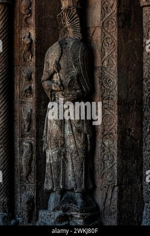 Figure sculptée en relief, maintenant sans tête, à l'entrée de la basilique du monastère de Santa Maria de Ripoll dans la province de Gérone, Catalogne, Espagne. L'entrée a été sculptée au milieu des années 1100 dans un style roman lombard. Banque D'Images