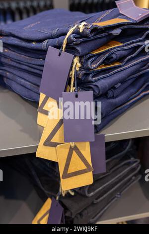 Gros plan sur des jeans denim empilés dans la boutique. Jeans une pile de paires pliées de pantalons bleus sur une étagère. Banque D'Images