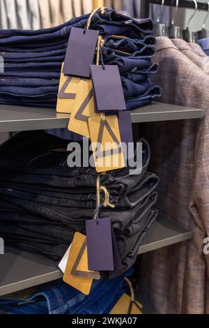 Gros plan sur des jeans denim empilés dans la boutique. Jeans une pile de paires pliées de pantalons bleus sur une étagère. Banque D'Images