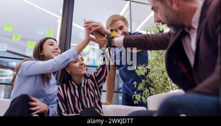 Des collègues d'affaires qui font un grand geste pour célébrer leur réussite. Un groupe diversifié d'individus assis étroitement ensemble sur un grand canapé s'engageant dans Banque D'Images