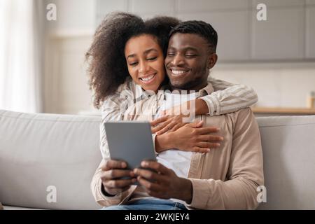 Aimant couple afro-américain millénaire aime surfer sur le Web sur tablette à l'intérieur Banque D'Images