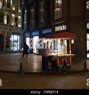 Istanbul, Turquie - 11 décembre 2023 : les filles de la région achètent du maïs grillé et des châtaignes dans une rue tard dans la soirée. Petite profondeur de champ, concentrez-vous sur une fille f Banque D'Images