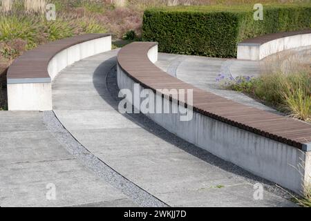 banc incurvé moderne en béton avec support en bois dans le parc Banque D'Images