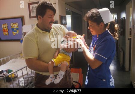 Infirmière Catherine Ellis à l'hôpital pour enfants Alder Hey, père et bébé. Liverpool, Angleterre vers 1988. ANNÉES 1980 ROYAUME-UNI HOMER SYKES Banque D'Images