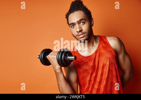 homme afro-américain sportif attrayant en uniforme de formation avec haltère et regardant la caméra Banque D'Images
