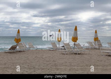 Plage déserte avec des fauteuils inclinables inutilisés avec un cargo en arrière-plan un jour couvert à Fort Lauderdale, en Floride Banque D'Images