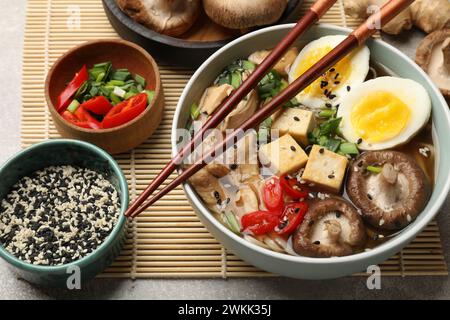 Bol de délicieux ramen et ingrédients sur la table grise. Soupe de nouilles Banque D'Images