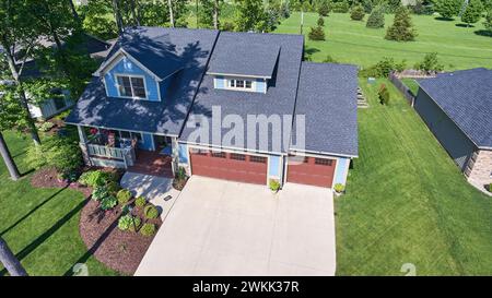 Vue aérienne de Blue Suburban Home avec portes de garage rouges dans un quartier serein Banque D'Images
