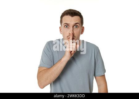 Jeune homme montrant signe de geste de silence sur fond blanc Banque D'Images