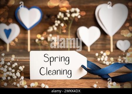 Étiqueter avec le texte anglais Spring Cleaning. Décoration blanche festive et atmosphérique comme des cœurs, des fleurs et Un arc bleu. Vintage, fond en bois avec Banque D'Images