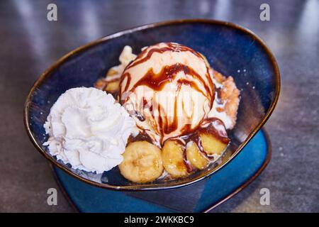 Gourmet Banana Split dans Blue Bowl avec bananes caramélisées et sirop de chocolat Banque D'Images