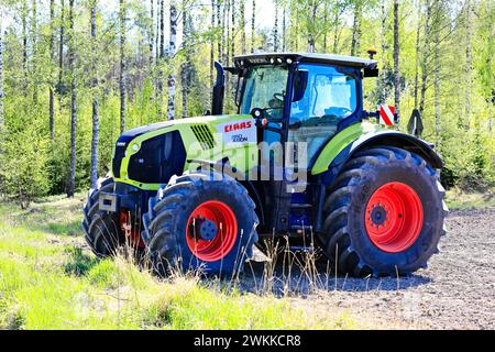 Tracteur CLAAS Axion 850 dans le champ sur une journée ensoleillée de printemps, fond vert de forêt de bouleau. Salo, Finlande. 20 mai 2023. Banque D'Images