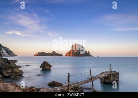 Une petite jetée en bois à Cala d'Hort avec une vue sur les rochers es Vedra en arrière-plan au lever du soleil Banque D'Images