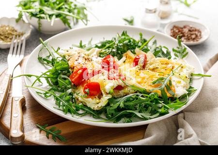 Œufs frits, omelette aux oignons, tomates et salade de roquette fraîche Banque D'Images