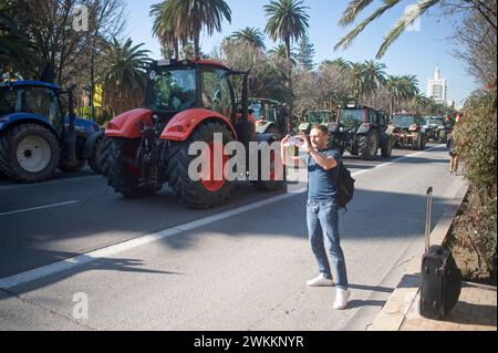 Malaga, Espagne. 21 février 2024. Un touriste est vu prendre des photos alors que des tracteurs sont garés dans une rue lors d'une manifestation d'agriculteurs contre la politique agricole européenne et pour de meilleures conditions de travail. Des centaines de tracteurs ont bloqué les rues principales de la ville pour protester contre les coûts de production élevés et la concurrence déloyale des pays non européens. (Photo de Jesus Merida/SOPA images/SIPA USA) crédit : SIPA USA/Alamy Live News Banque D'Images