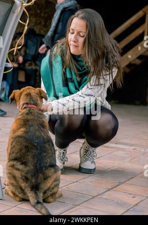 Portrait d'une jeune fille assise sur le sol jouant avec un chiot. Vertical Banque D'Images