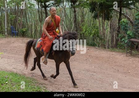 CHIANG RAI, THAÏLANDE - 21 mai 2016 : jeune moine bouddhiste à cheval dans le temple du cheval d'or (Wat Phra Archa Thong). Moine portant un o traditionnel Banque D'Images