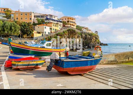 Petits bateaux de pêche colorés de bleu, jaune et rouge bordent le petit port de plaisance du petit village de pêcheurs de Câmara de Lobos, Madère Portugal Banque D'Images