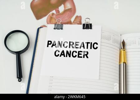 Concept médical. Sur la table, il y a une loupe et un bloc-notes avec l'inscription - cancer du pancréas Banque D'Images