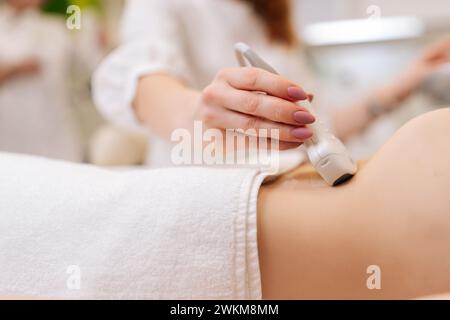 Gros plan de jeune femme méconnaissable subit un diagnostic échographique des organes abdominaux dans la clinique moderne. Médecin professionnel faisant l'estomac Banque D'Images