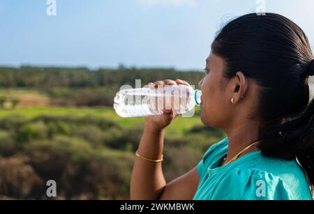 Une jeune femme randonneuse prend une pause pour se réhydrater avec une boisson fraîche de sa bouteille d'eau réutilisable Banque D'Images