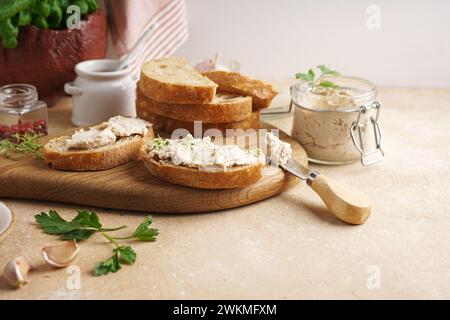 Pâté maison, tartiner ou mousse dans un bocal en verre avec du pain tranché et des herbes, fond concret. Banque D'Images