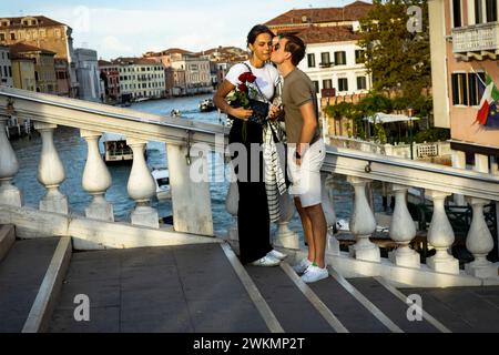 Les gens viennent aux ponts sur Venise pour être vus et admirer le coucher du soleil. Un jeune couple amoureux sur un pont sur le Grand canal. Banque D'Images