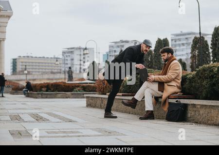 Silhouettés sur un ciel nuageux, deux hommes élégants s'engagent dans une conversation sérieuse sur un ordinateur portable, peut-être des collègues discutant du travail. Banque D'Images