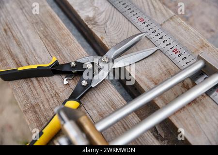 photo d'objet de nouvelles pinces métalliques couchées à côté du ruban à mesurer sur une table en bois à l'extérieur du site Banque D'Images