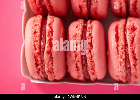 Macarons set.macarons roses dans une boîte en carton blanc sur fond rose. Bonbons et desserts. Pâtisseries françaises. Fond de macarons multicolores Banque D'Images