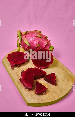 Ensemble de fruits de dragon rouge avec service appétissant isolé sur fond rose. Vue de dessus, main Banque D'Images