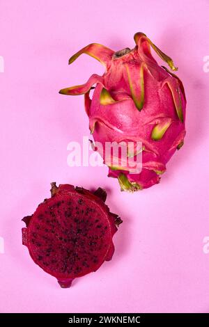 Ensemble de fruits de dragon rouge avec service appétissant isolé sur fond rose. Vue de dessus, main Banque D'Images