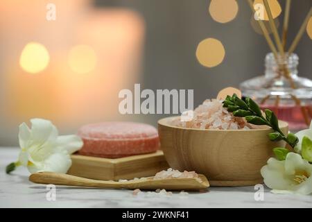 Belle composition avec différents produits de spa et des fleurs sur une table en marbre blanc sur fond flou Banque D'Images