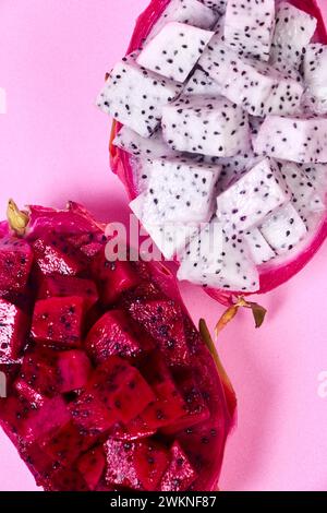 Ensemble de fruits de dragon rouge avec service appétissant isolé sur fond rose. Vue de dessus, main Banque D'Images