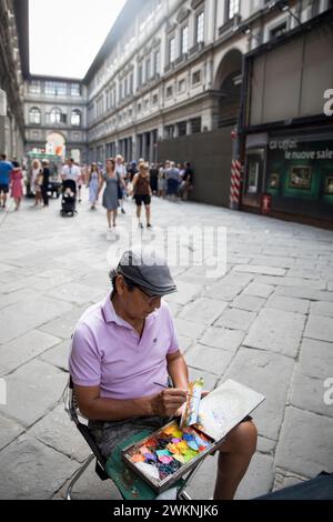 Un artiste de rue crée une petite peinture sur toile représentant Florence, en Italie, à l'extérieur de la galerie des Offices. Banque D'Images