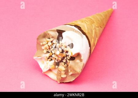 Crème glacée au chocolat et à la vanille dans un cône de gaufre sur fond rose Banque D'Images