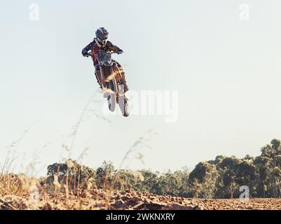 Moto, personne et plein air pour sauter en course sur sentier pour la compétition, l'air et les jeux sur terre. Racer, moto et casque pour concours, moteur Banque D'Images