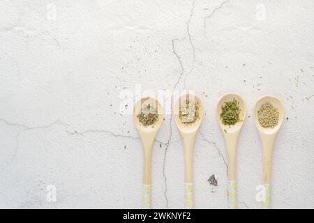 Quatre cuillères en bois avec diverses épices sur une surface de vaisselle blanche Banque D'Images