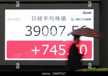 Un passant marche devant la moyenne des parts de Nikkei du Japon affichée sur un panneau à Tokyo, au Japon, le 22 février 2024. La moyenne des actions Nikkei a dépassé les 39 000 jeudi pour la première fois, battant le précédent record de tous les temps enregistré en 1989. Crédit : Yohei Osada/AFLO/Alamy Live News Banque D'Images