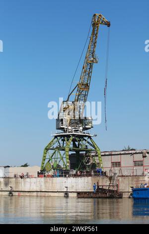 Grue à portail vert jaune est sous le ciel bleu sur une journée ensoleillée, photo verticale Banque D'Images