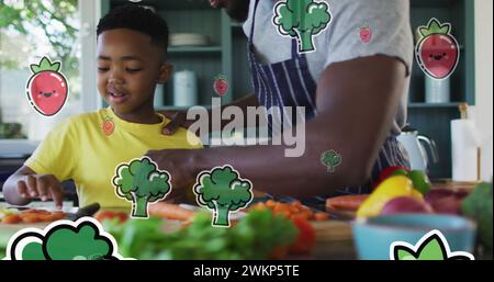 Image de légumes flottant sur un heureux père afro-américain et son fils préparant un repas Banque D'Images