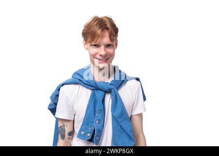 jeune homme roux positif avec une courte coupe de cheveux avec un tatouage sur les bras portant un t-shirt blanc Banque D'Images