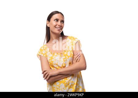 european positif charmante dame brune avec les cheveux lâches portant un t-shirt jaune avec un imprimé de fleurs Banque D'Images