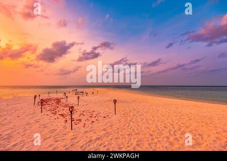 Incroyable proposition d'anniversaire romantique dîner plage sur des bougies de sable sous le ciel du coucher du soleil. Amour romantique, dîner de destination de luxe, configuration de table exotique Banque D'Images