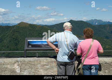 Couple de touristes regardant un panneau de panorama et paysage de montagne du parc régional Campo dei Fiori de Sacro Monte de Varèse, Lombardie, Italie Banque D'Images