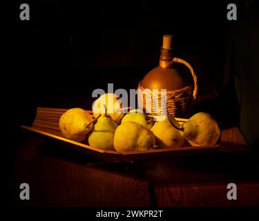 Poires jaunes mûres dans un vase en bois sur la table, à côté d'une cruche de vin. Nature morte. Banque D'Images