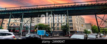 New York, USA ; 3 juin 2023 : train aérien typique et voies de tramway du Bronx, un quartier de la Big Apple, sous un ciel orange lever de soleil. Banque D'Images