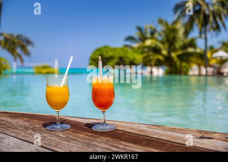 Cocktails colorés servis dans un hôtel de luxe tropical aux Maldives. Côté piscine, palmiers flous et chaises longues et lumière du soleil. Journée ensoleillée et lumineuse Banque D'Images