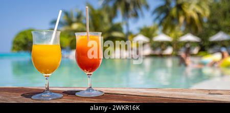 Cocktails colorés servis dans un hôtel de luxe tropical aux Maldives. Côté piscine, palmiers flous et chaises longues et lumière du soleil. Journée ensoleillée et lumineuse Banque D'Images