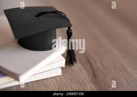 Chapeau de graduation sur le dessus de la pile de livres sur une table en bois. Copier l'espace pour le texte. Concept d'éducation. Banque D'Images